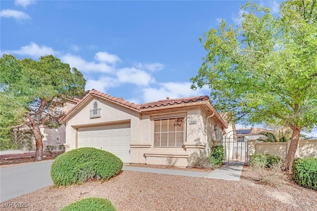 view of front of property featuring a garage, a tile roof, driveway, a gate, and stucco siding