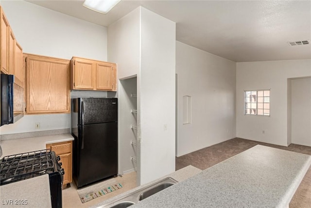 kitchen featuring light countertops, visible vents, open floor plan, a sink, and black appliances