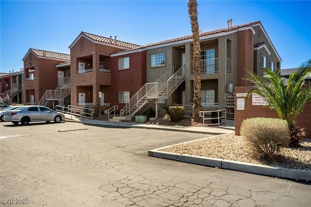 view of property with stairs and uncovered parking