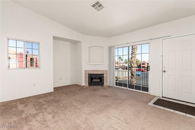 unfurnished living room featuring carpet floors, visible vents, and a tiled fireplace