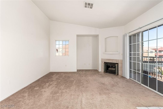 unfurnished living room with carpet, visible vents, vaulted ceiling, and a tile fireplace