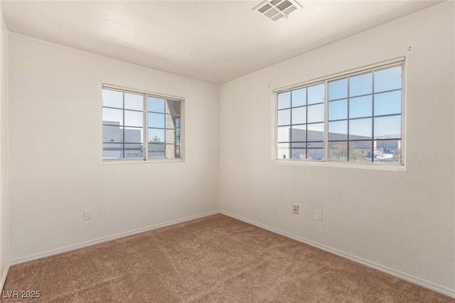 unfurnished room with carpet, visible vents, and baseboards