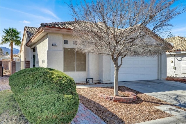 view of front of home featuring an attached garage, driveway, a tile roof, and stucco siding