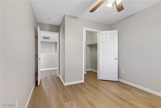 unfurnished bedroom with baseboards, visible vents, a spacious closet, light wood-type flooring, and a closet