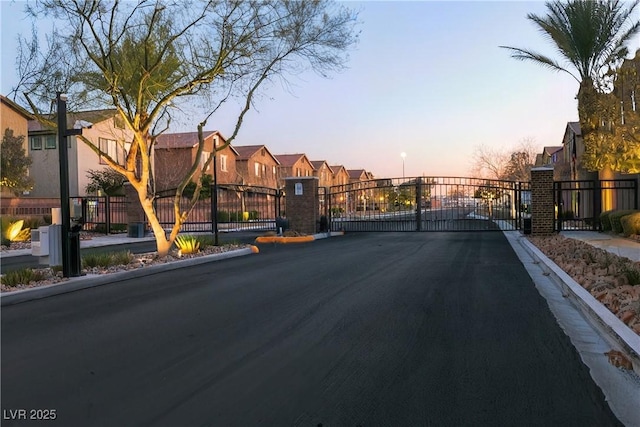 view of road with a residential view, a gate, curbs, and a gated entry