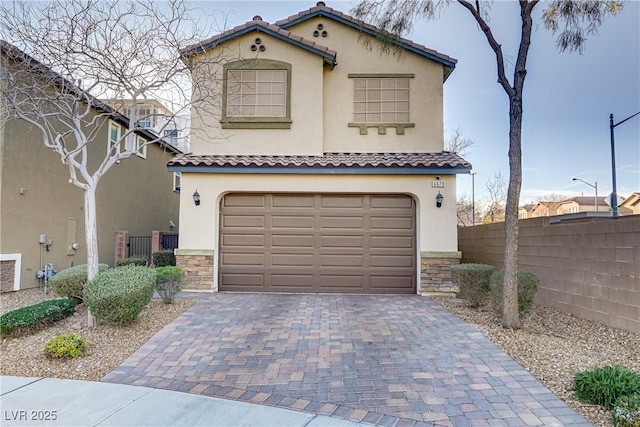 mediterranean / spanish-style home with a garage, stone siding, decorative driveway, and stucco siding