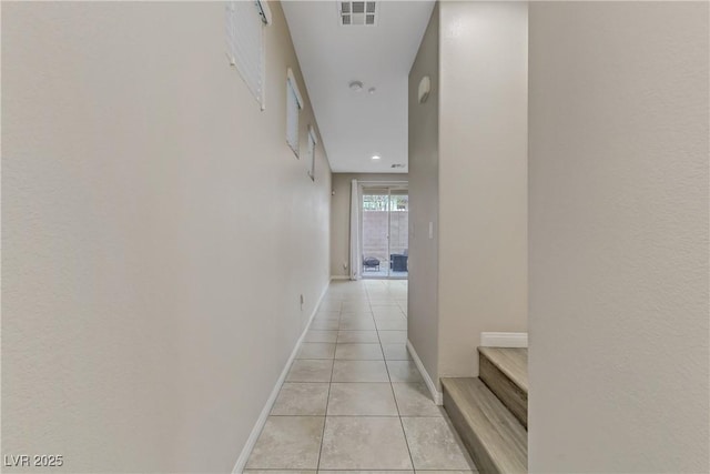 corridor with baseboards, visible vents, and light tile patterned flooring