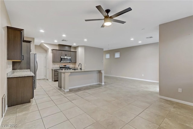 kitchen featuring a center island with sink, appliances with stainless steel finishes, open floor plan, a sink, and recessed lighting