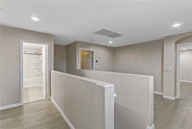 corridor featuring light wood finished floors, recessed lighting, visible vents, an upstairs landing, and baseboards