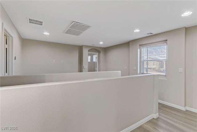 corridor with light wood-style floors, baseboards, visible vents, and recessed lighting