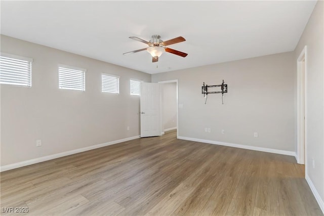 empty room featuring light wood-type flooring, a healthy amount of sunlight, ceiling fan, and baseboards