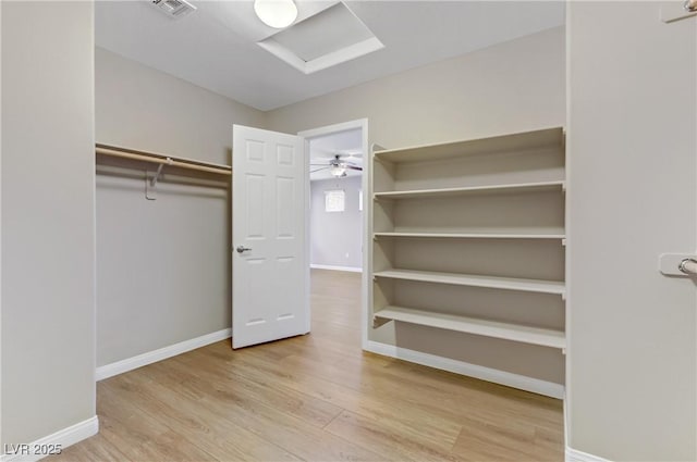 spacious closet with light wood finished floors, visible vents, and attic access