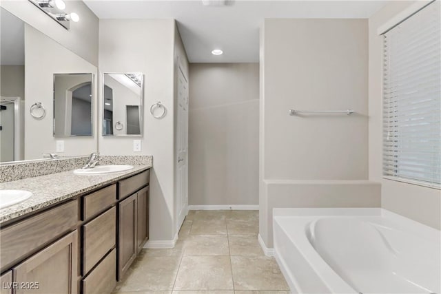 bathroom with double vanity, baseboards, tile patterned floors, a sink, and a bath