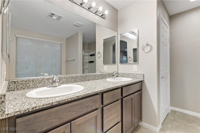 bathroom with double vanity, a sink, visible vents, and baseboards