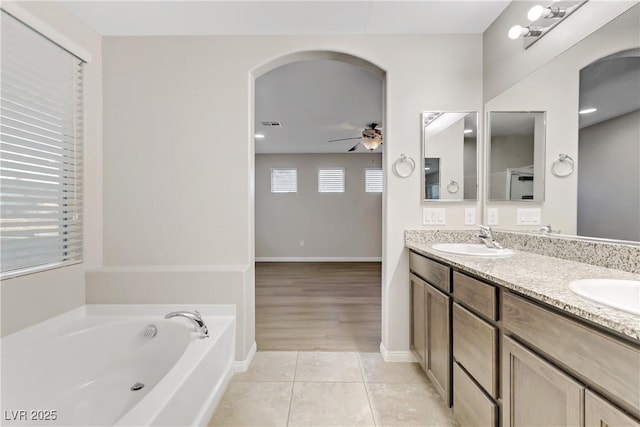 bathroom with a garden tub, double vanity, a sink, ceiling fan, and tile patterned flooring