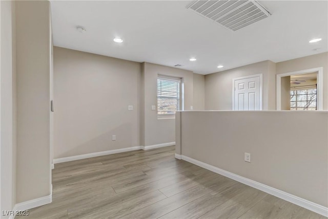 empty room with light wood-style flooring, recessed lighting, visible vents, and baseboards