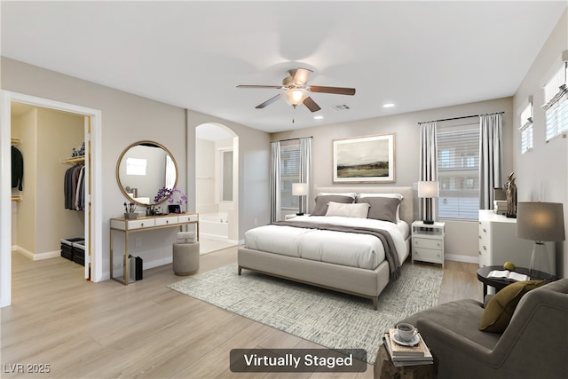 bedroom featuring light wood finished floors, visible vents, arched walkways, and baseboards