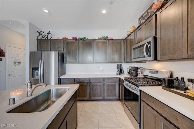 kitchen with dark brown cabinetry, visible vents, stainless steel appliances, light countertops, and a sink