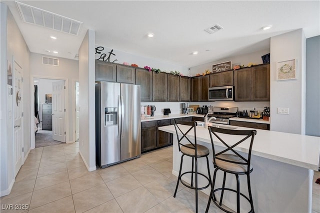 kitchen with stainless steel appliances, dark brown cabinets, and visible vents