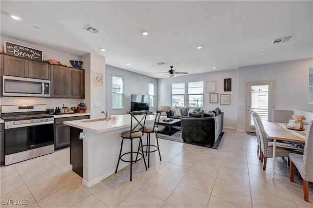 kitchen featuring appliances with stainless steel finishes, light countertops, visible vents, and a kitchen breakfast bar