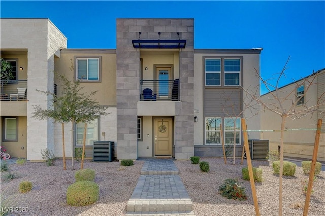 view of front facade featuring stone siding, stucco siding, and central AC unit