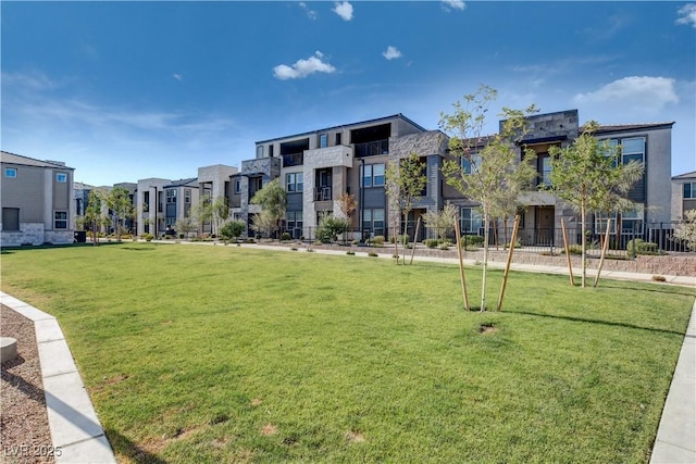 view of community featuring a yard, fence, and a residential view