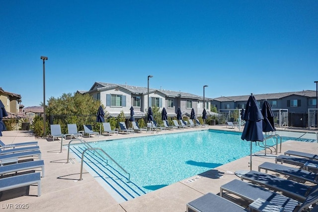 community pool with a residential view, fence, and a patio