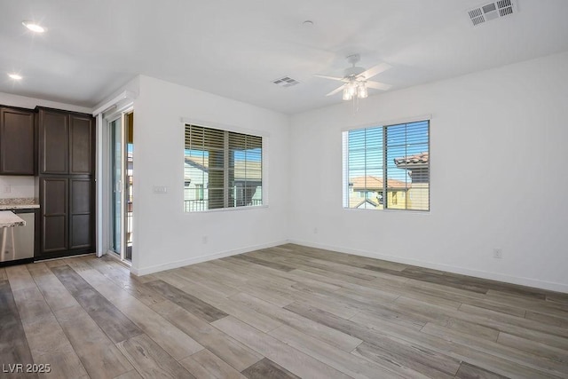 unfurnished room with light wood-type flooring, visible vents, and baseboards