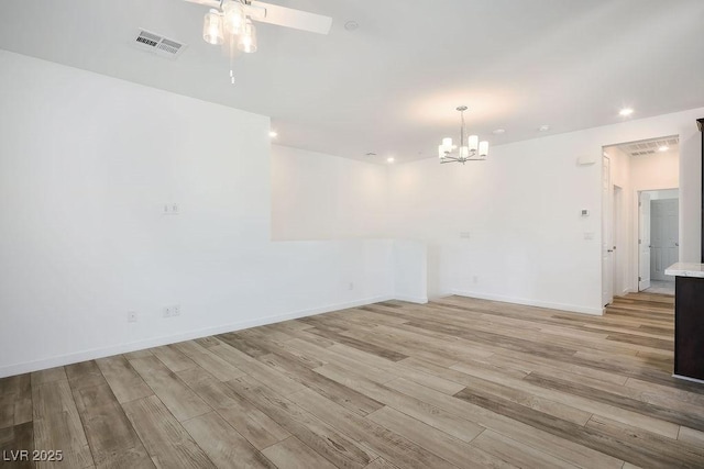 empty room with recessed lighting, visible vents, light wood-type flooring, baseboards, and ceiling fan with notable chandelier