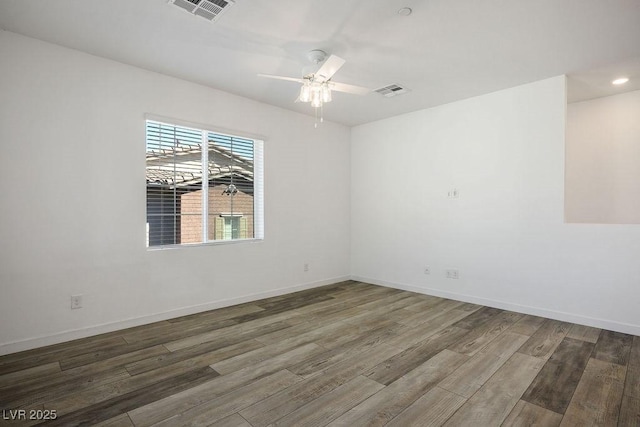 empty room featuring ceiling fan, wood finished floors, visible vents, and baseboards