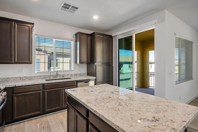 kitchen featuring light stone counters, a sink, visible vents, dark brown cabinets, and appliances with stainless steel finishes