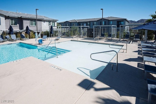 pool with a patio, fence, and a residential view