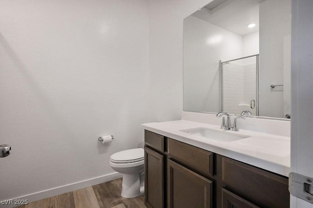 full bath with toilet, wood finished floors, vanity, baseboards, and an enclosed shower