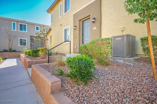 doorway to property featuring stucco siding and central air condition unit