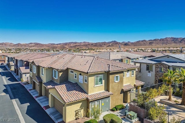 exterior space featuring a residential view, a tiled roof, fence, a mountain view, and stucco siding