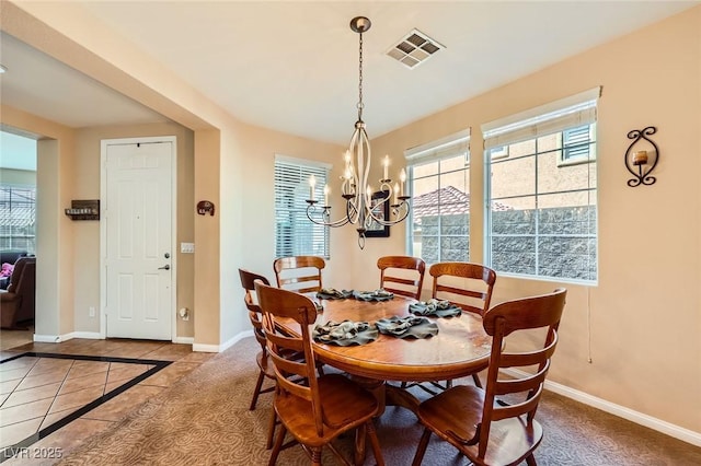 dining area featuring tile patterned flooring, baseboards, visible vents, and a chandelier