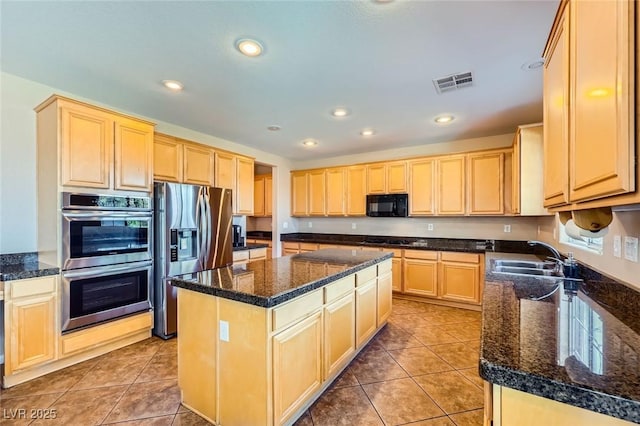 kitchen with light brown cabinetry, stainless steel appliances, and a sink