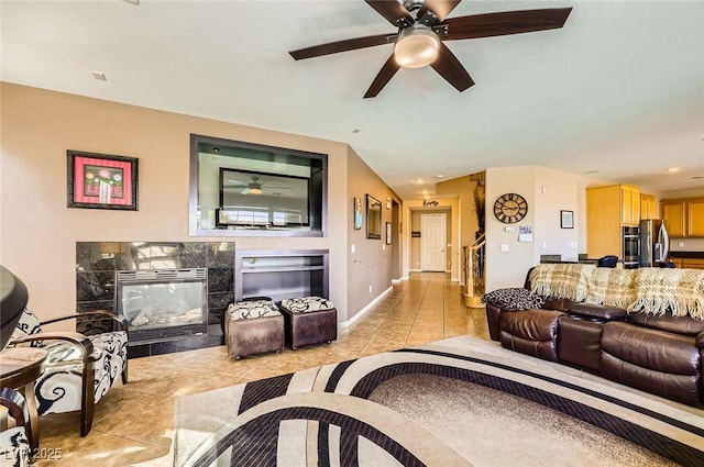 living room with light tile patterned floors, a fireplace, baseboards, and a ceiling fan