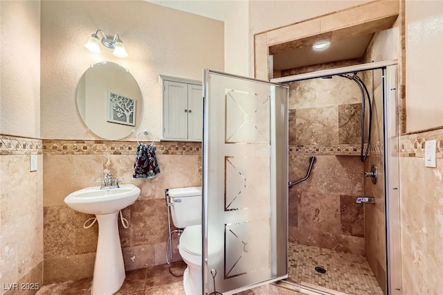 full bath with toilet, tile walls, wainscoting, and a shower stall