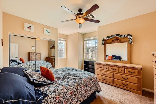 bedroom with a closet, light colored carpet, and a ceiling fan