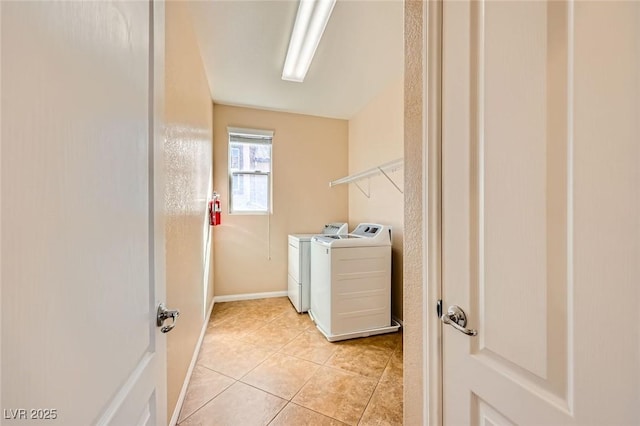 washroom with laundry area, light tile patterned floors, separate washer and dryer, and baseboards