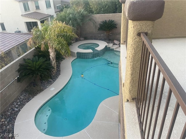 view of pool featuring a fenced backyard and a pool with connected hot tub