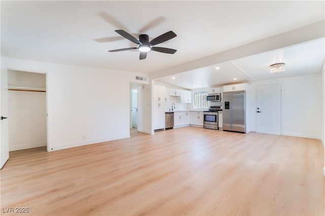 unfurnished living room with light wood finished floors, visible vents, baseboards, ceiling fan, and a sink