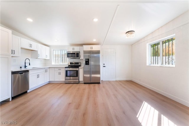 kitchen featuring stainless steel appliances, light countertops, white cabinetry, and light wood-style floors