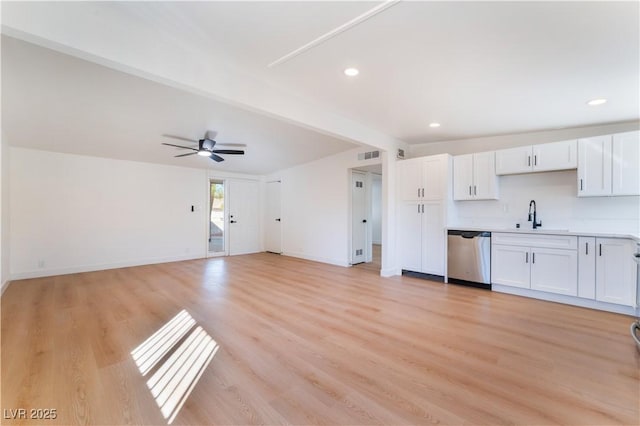 kitchen featuring beam ceiling, light countertops, stainless steel dishwasher, white cabinetry, and a sink