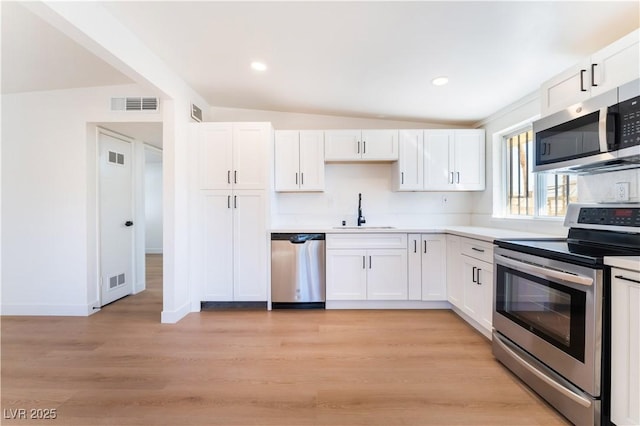 kitchen with stainless steel appliances, light countertops, white cabinetry, and a sink