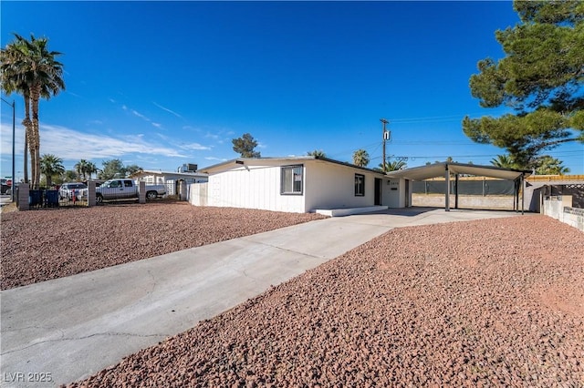 ranch-style home featuring driveway, fence, and a carport