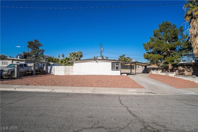 view of front of property featuring driveway, fence, and a carport