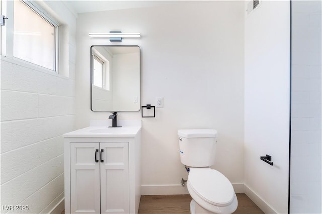 bathroom featuring baseboards, vanity, toilet, and wood finished floors