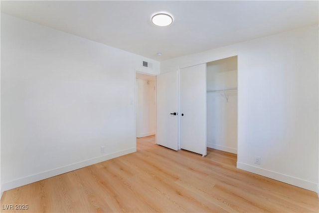 unfurnished bedroom featuring wood finished floors, visible vents, and baseboards